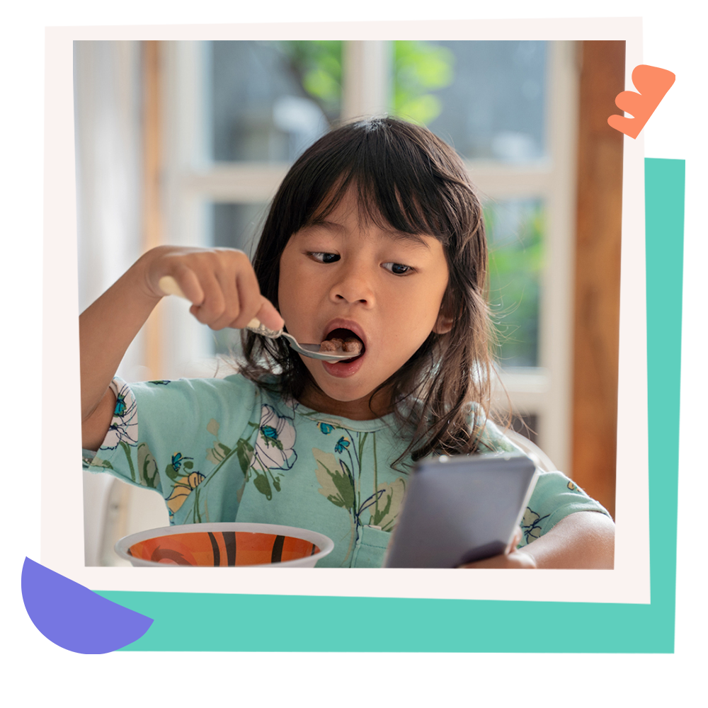 A young girl eating cereal while watching something on a smartphone.